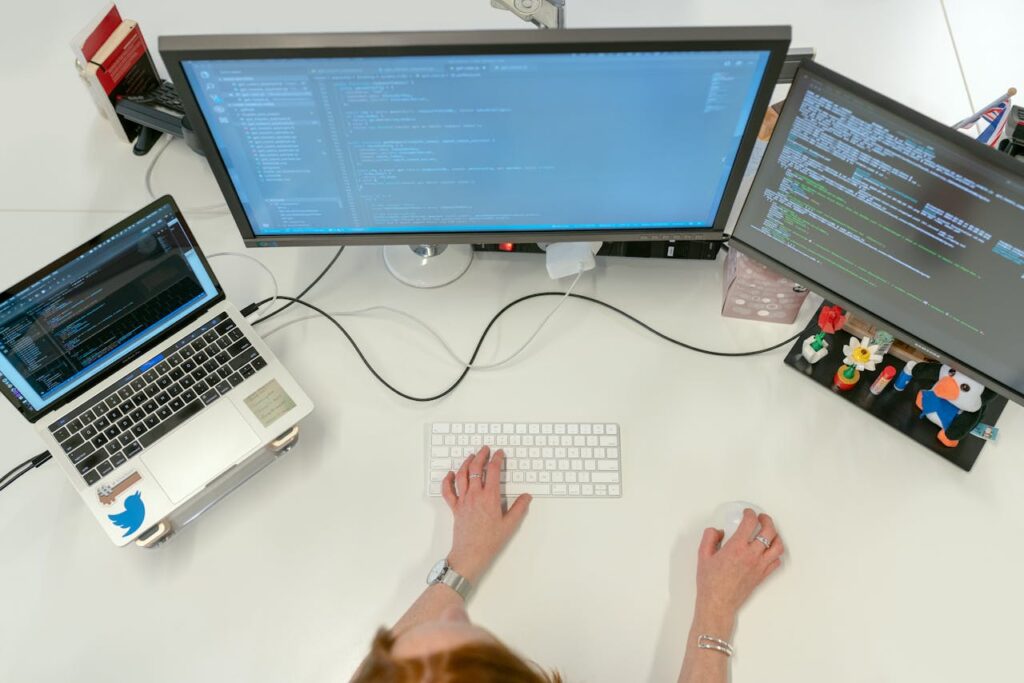 pexels-photo-3861972 A female software engineer coding on dual monitors and a laptop in an office setting.